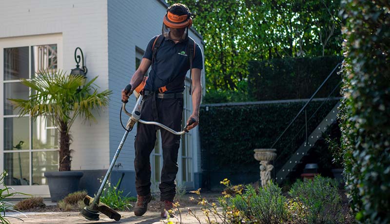 Trädgårdsskötare med grästrimmer som arbetar enligt AFF-baserat entreprenadavtal
